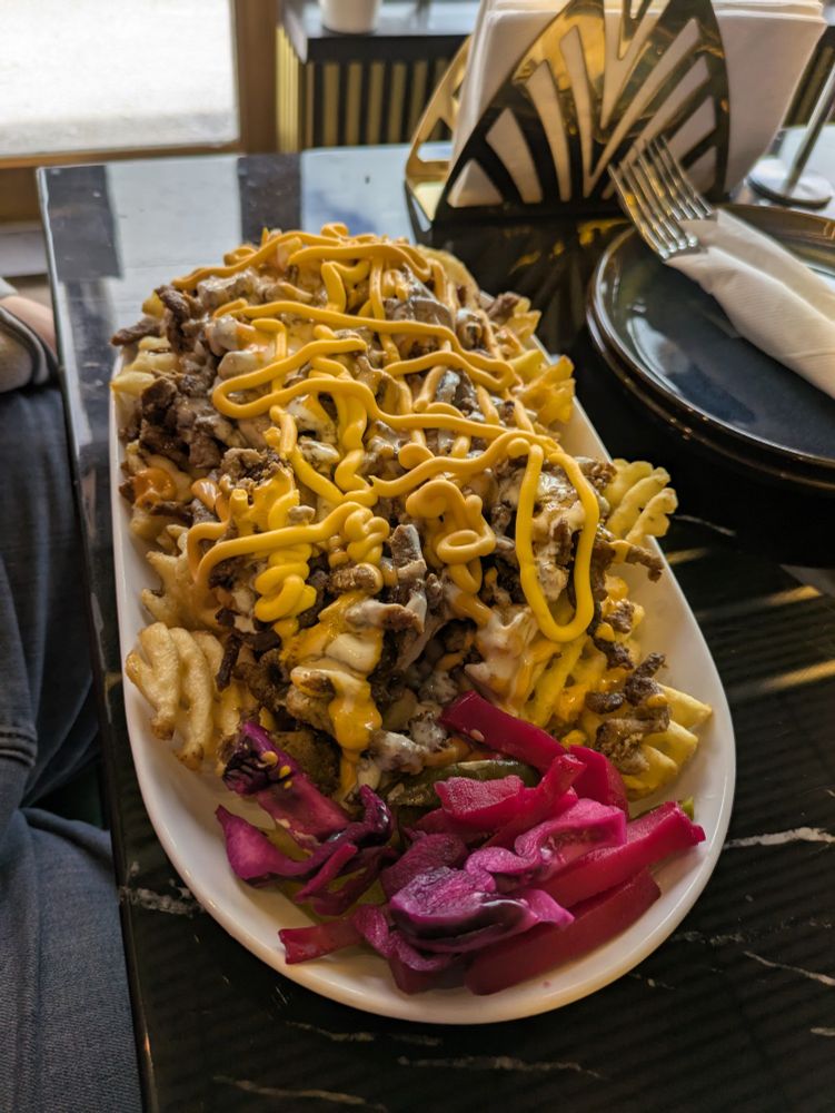 My husband's loaded beef plate. It has waffle cut fries, shawarma beef, and a spicy cheese sauce, plus various picked veg on the side. 