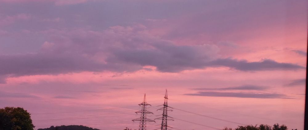 Abendhimmel im leuchtendem Ultraviolett, Wolken, Strommasten, ein Baumwipfel