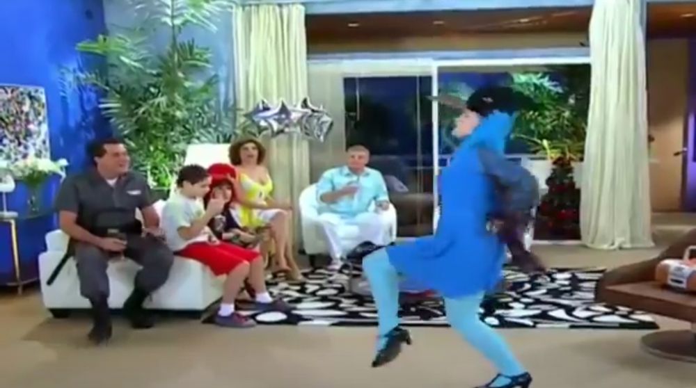 Bozena (personagem de Toma Lá Dá Cá) fazendo a dança da Gralha Azul vestida de Gralha Azul diante dos outros personagens da série