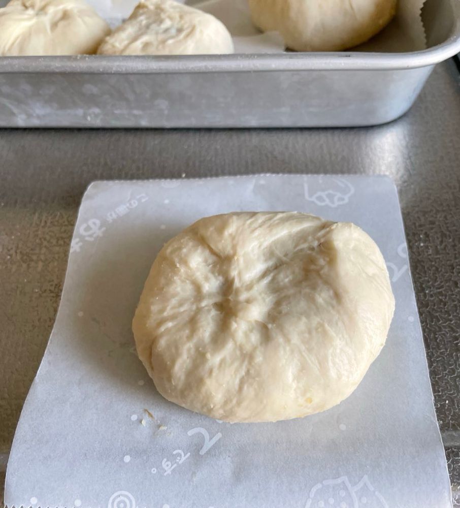 蒸す前の豚饅。タネが隙間なく包まれている。クッキングシートの切れ端が敷いてある。