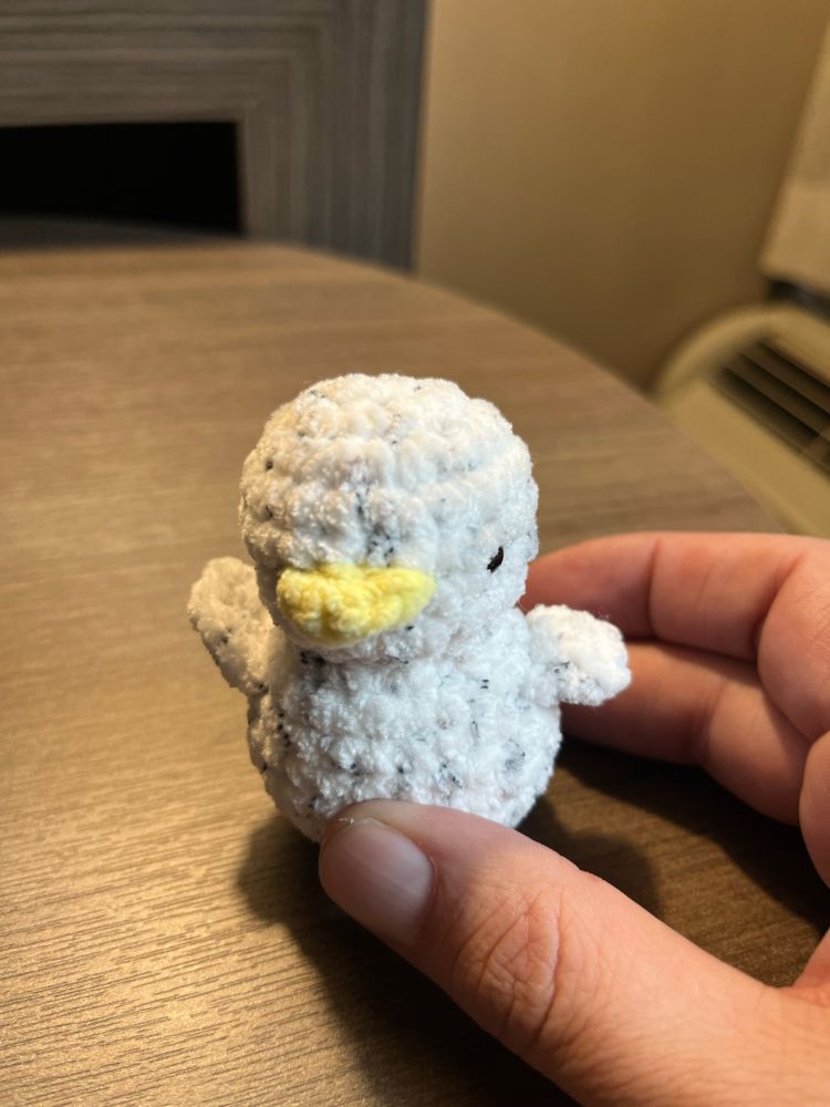Tiny cute knitted white duckling with yellow beak. 