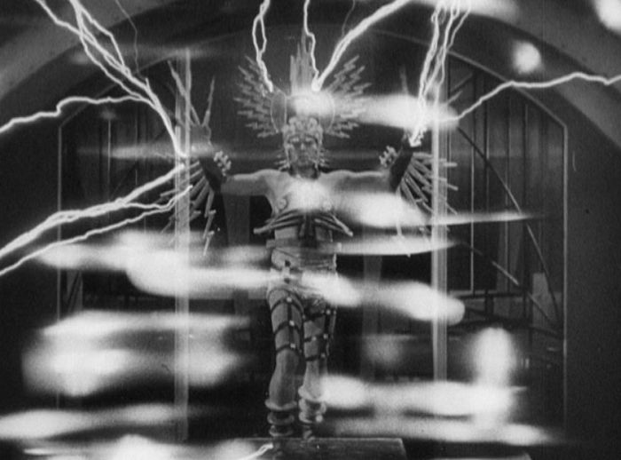Black and white image of a man in a fantastical lightning-themed costume, electricity crackling around him