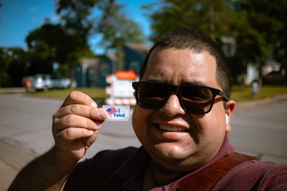 Picture of Hector outside holding a “I voted” sticker.