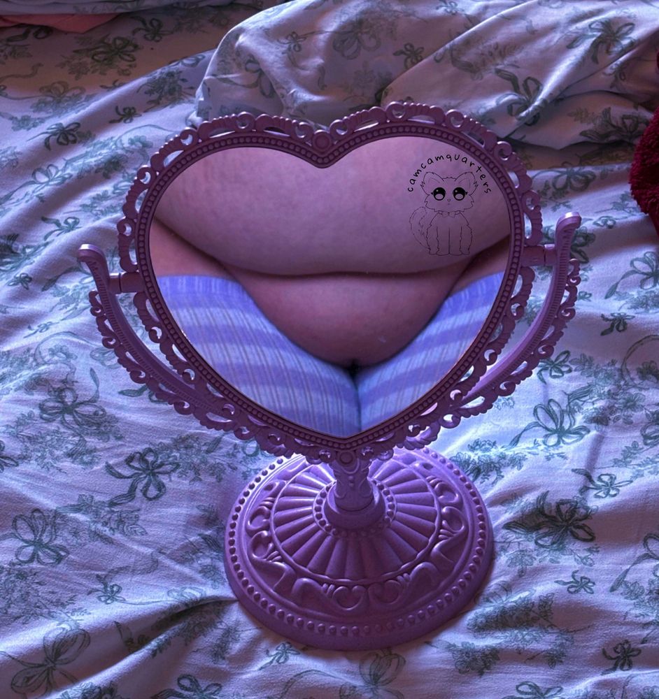 Camcam’s pussy, lower belly, and upper thighs are framed within a purple heart shaped mirror. She’s wearing only purple and white striped thigh highs. 