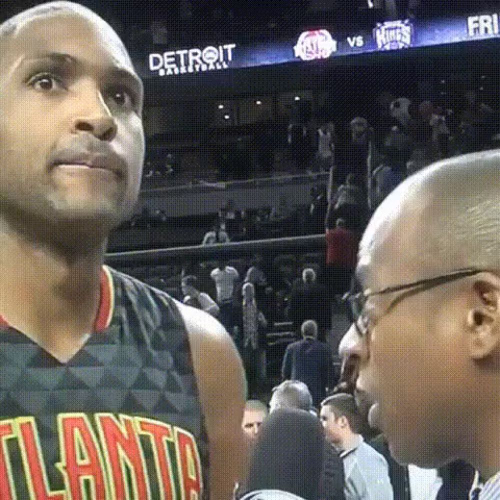 a basketball player wearing a atlanta jersey is talking to a reporter .