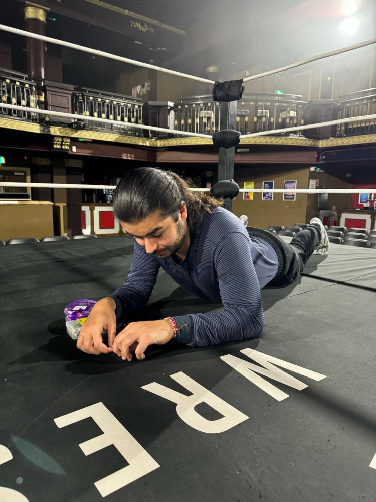 Me, laying down, sewing up the canvas of a wrestling ring