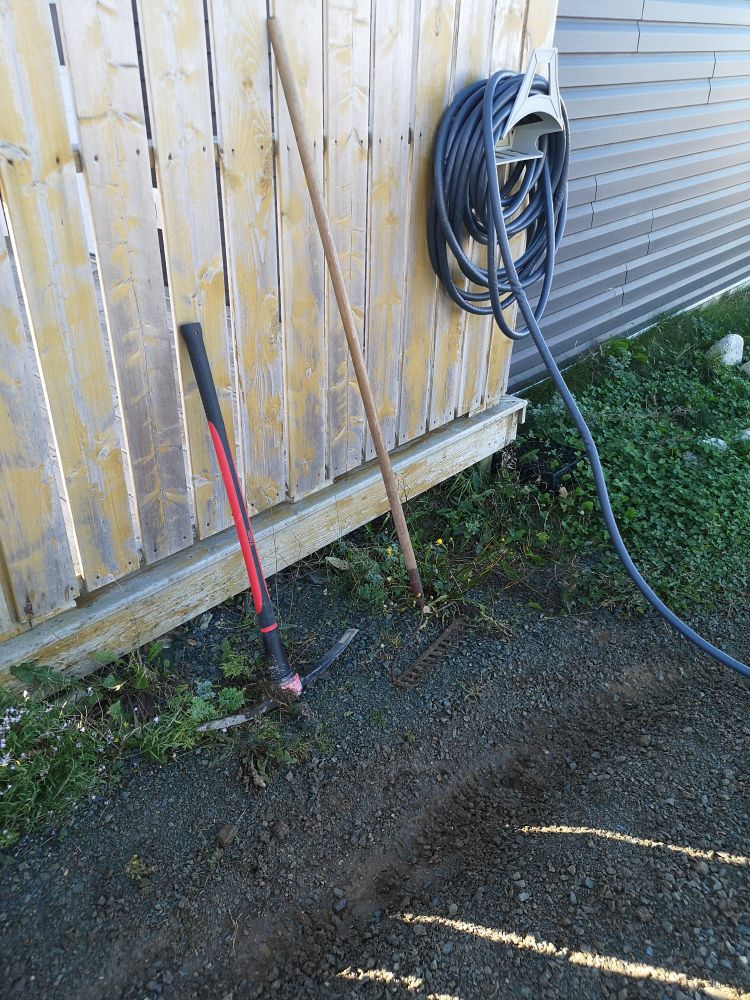 A little trench that's two inches deep and four inches wide. Next to it is a pick and a firm rake.