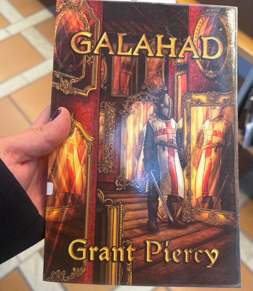 Me holding the book “Galahad” by Grant Piercy.