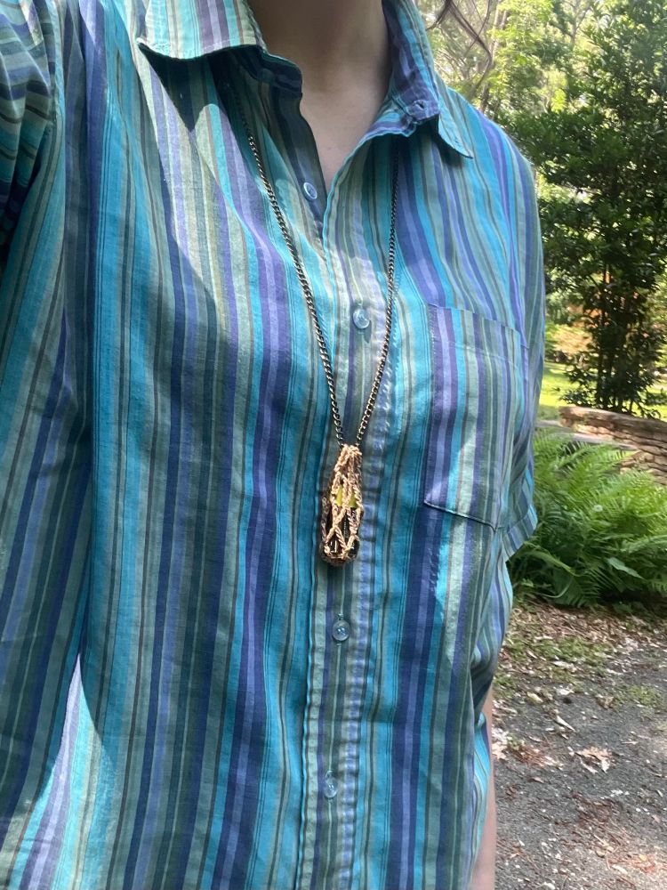 Selfie from the neck down; I’m wearing a necklace with a crocheted mesh bag. Inside the bag is a mysterious object.