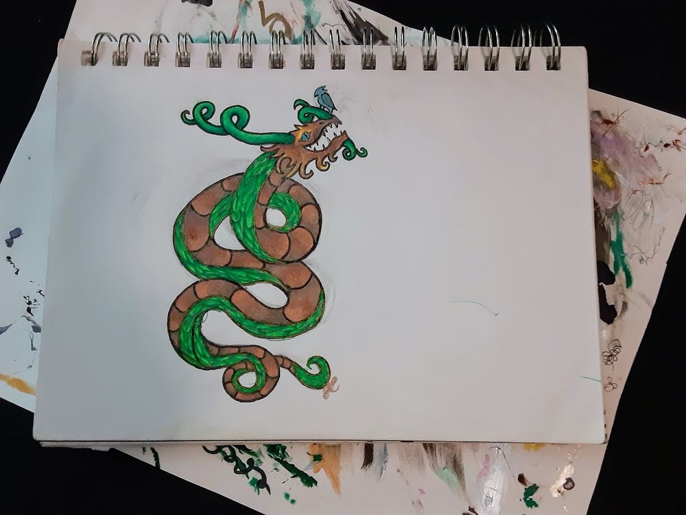 A serpentine dragon looking up happily at a bird on its nostrils. With green scales and a brown belly, this guy was designed to emulate a tree.