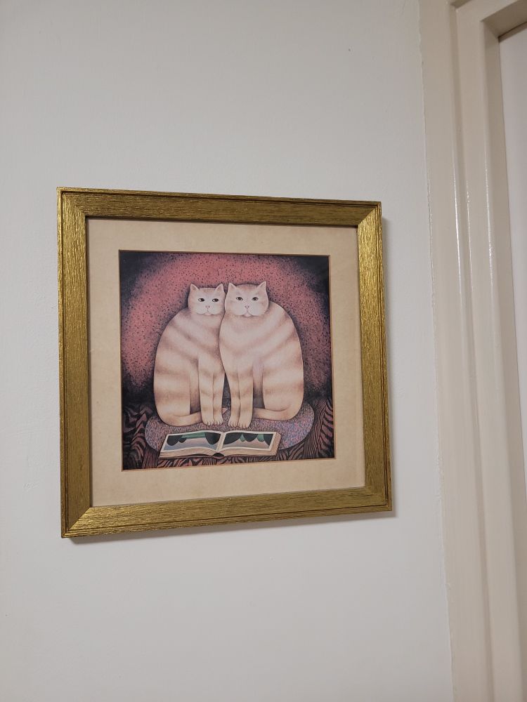 A painting of two ginger and white striped cats sitting together in front of a book.  