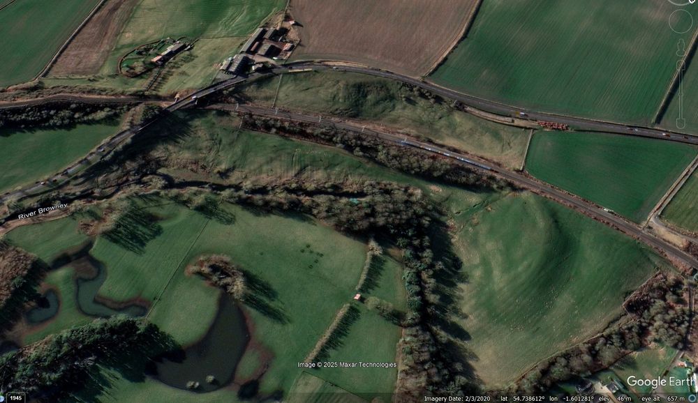 Google Earth image from 2020 showing the Browney Curve landslide site.  The East Coast Mainline railway line runs across the landslide. The image shows highly distrurbed ground on both sides of the track.