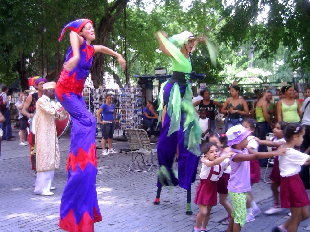 Stilt dancers and primary school children dancing in an outdoor cafe. 