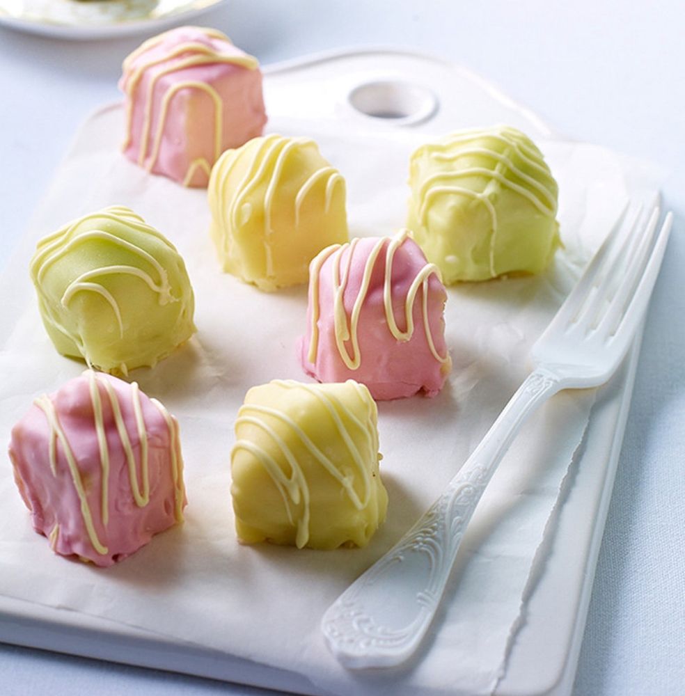 A selection of fondant fancies - small squares of sponge cake with a dollop of butter cream on top, covered in icing. 