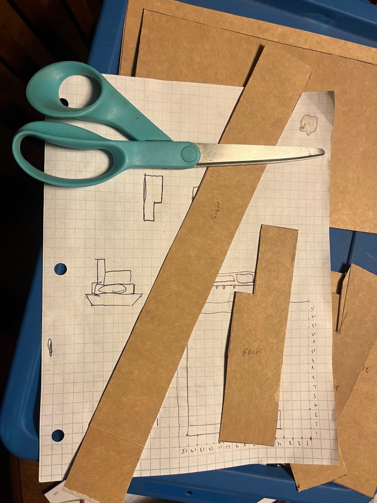 Cardboard house templates on graph paper next to scissors