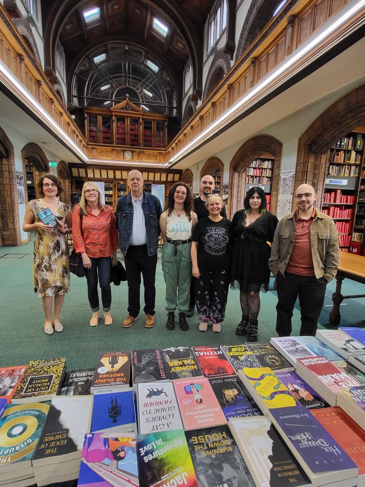 A group of writers standing together with a book table in front of them. 