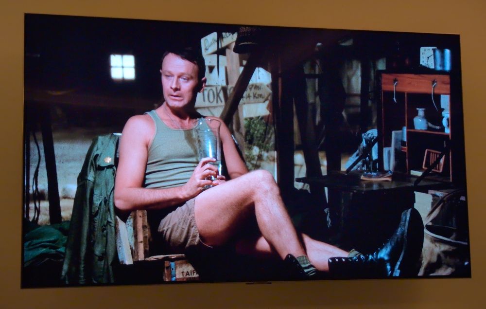 Foto vom TV. Szene aus der Serie M*A*S*H: Burns sitzt früh am Morgen noch betrunken im Zelt. 