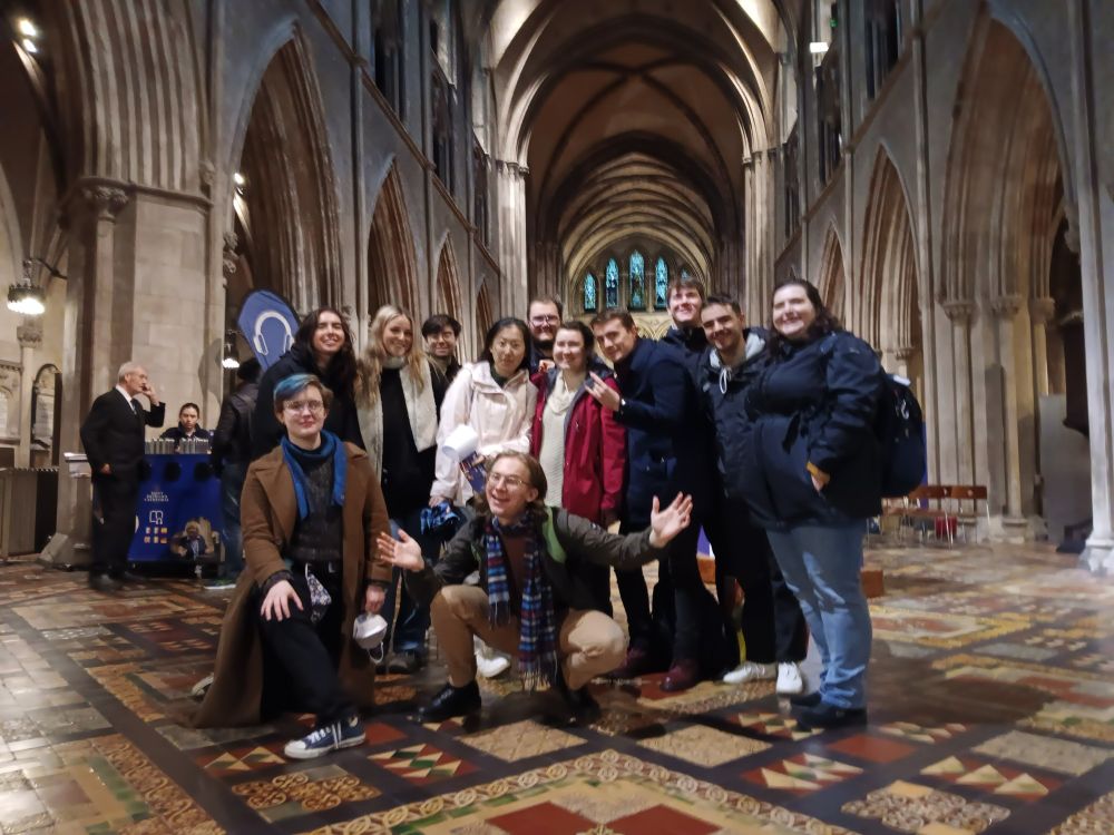 A group of twelve people mainly in their early 20s in the nave of a Gothic curch 