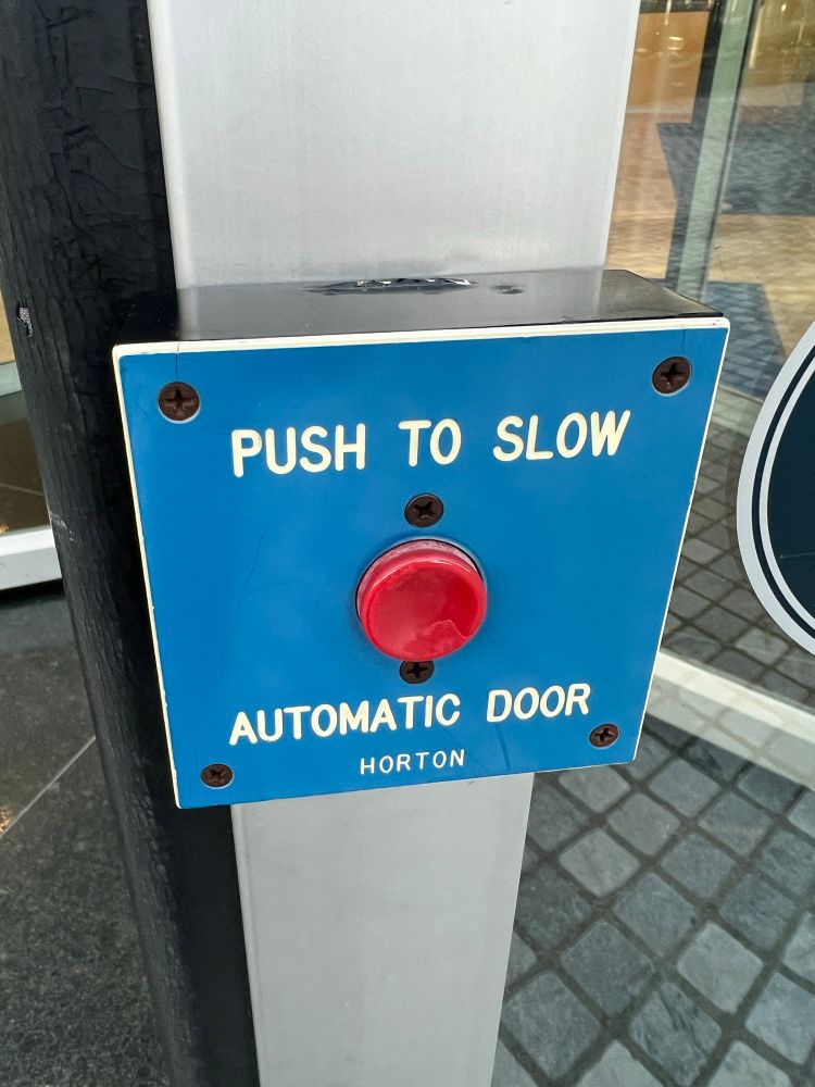Picture of a red button with text saying “Push to slow automatic door” and the brand name “Horton”