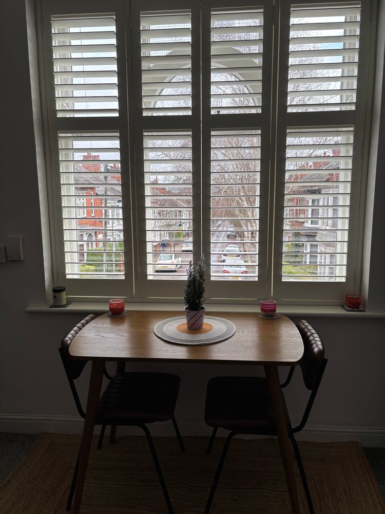 A small Christmas tree on a table in front of a window. 