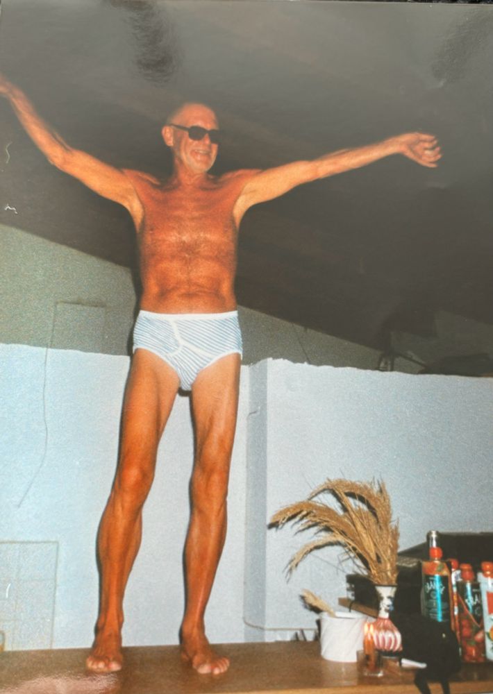 My dad standing on the counter of a bar. Dressed in only a pair of underpants. Arms in air. Looking happy. 