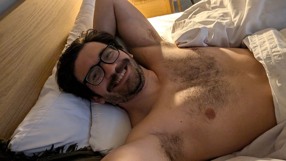 A selfie taken from bed. The poster is wearing glasses because he hasn't started his day and no shirt because he doesn't want to start his day. 