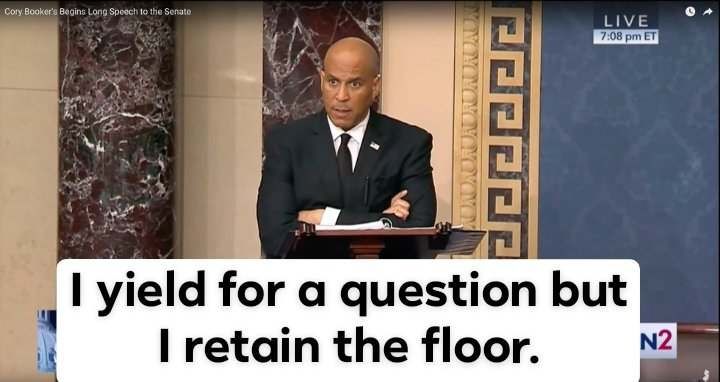 Image description, a picture of Senator Cory Booker on the senate floor giving a record-breaking filibuster, with a caption reading: I yield for a question but I retained the floor. 