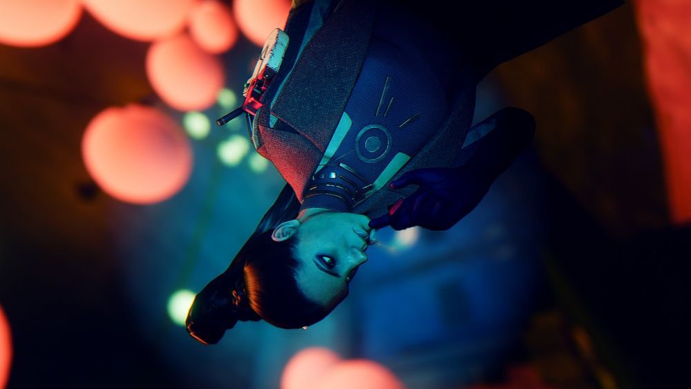 Fia, a woman with long black hair tied up in a high ponytail, holds a hand to her face and looks inquisitively into the distance, a backdrop of colorful paper lanterns framing the scene. Fia Zborowska is one of the Visionaries in DEATHLOOP, and the chief provisioner and art director of the AEON Program. A handheld radio is mounted on the shoulder of her jacket. 