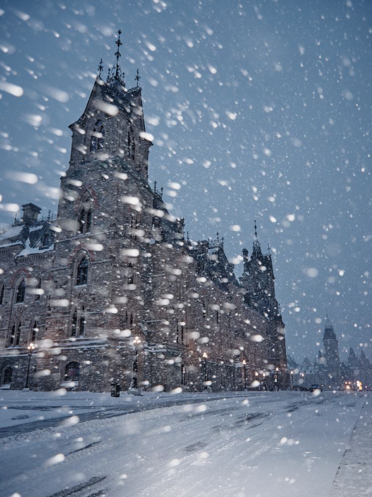 A photograph of the West Block of Canada's Parliament Buildings in a snowstorm at night.