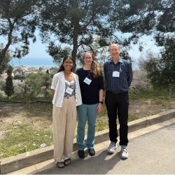 Odara and colleagues posing for a photo with the sea and a town in the distance behind them