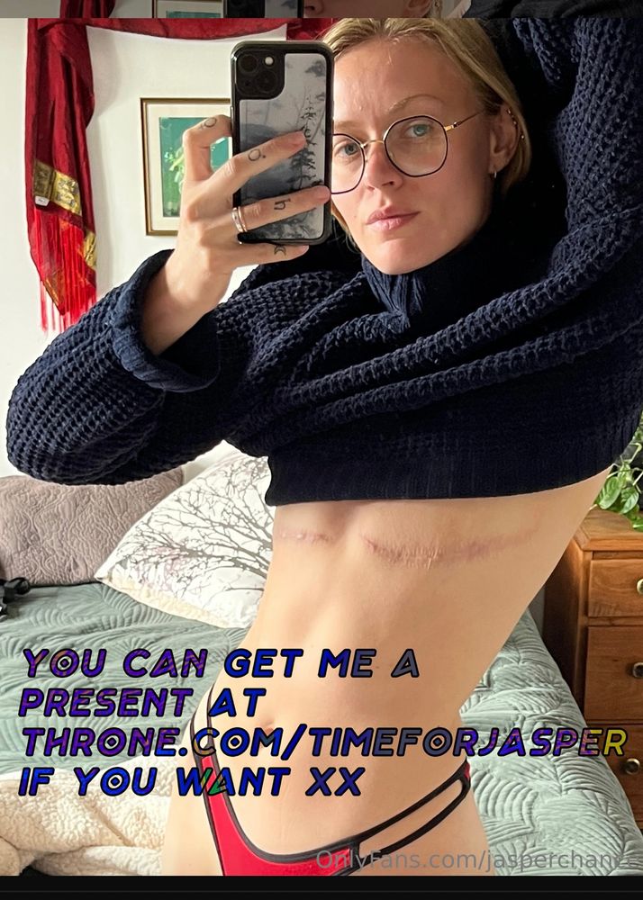 A selfie of Jasper from 3/4 side lifting their shirt up to reveal their top surgery scars. Text overlay says “You can get me a present at throne.com/timeforjasper if you want xx”