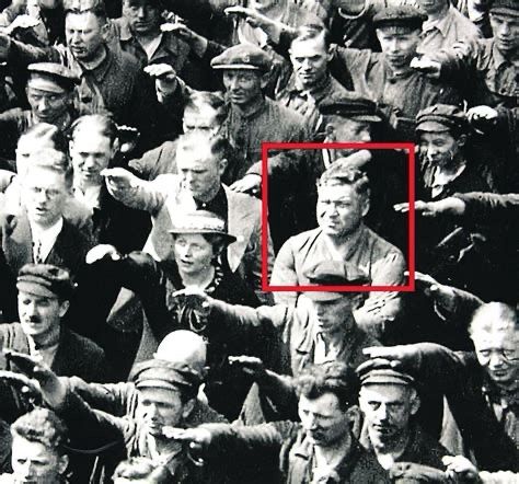 Schwarz Weiß Bild, eine Masse an Menschen zeigt den Hitler Gruß, nur ein einziger Mann nicht.