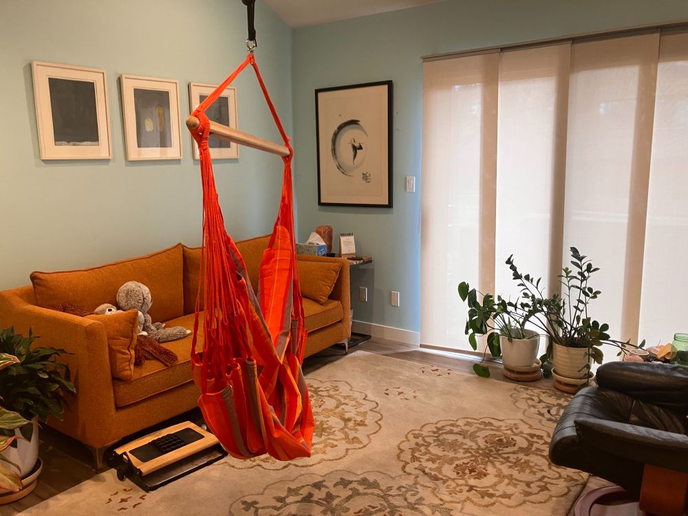 Serene space with couch, plants, calming images, and swing for sitting.