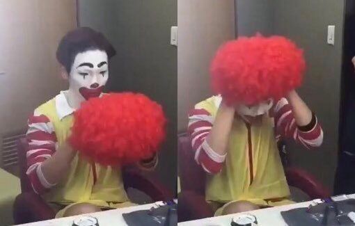Man sadly putting on a Ronald McDonald wig