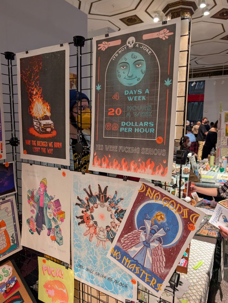 Several posters, one of which says "not joke/4 days a week/20 hours a week/69 dollars per hour/ YES WE'RE FUCKING SERIOUS" with flames below and a moon above