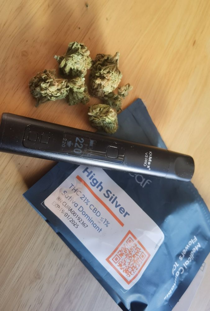 Image contains a dry herb vaporiser, a pouch of High Silver, 21% THC medical cannabis and some cannabis flower on a table
