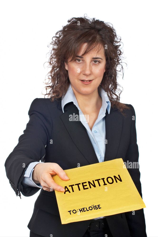 A stock photo of a businesswoman holding out an envelope towards the camera. The envelope has text superimposed on it. Large lettering in all capitals reads "attention". Smaller handwritten print lettering in a corner reads "To: Heloïse"