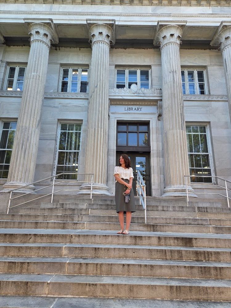 a woman on the steps of a stone library