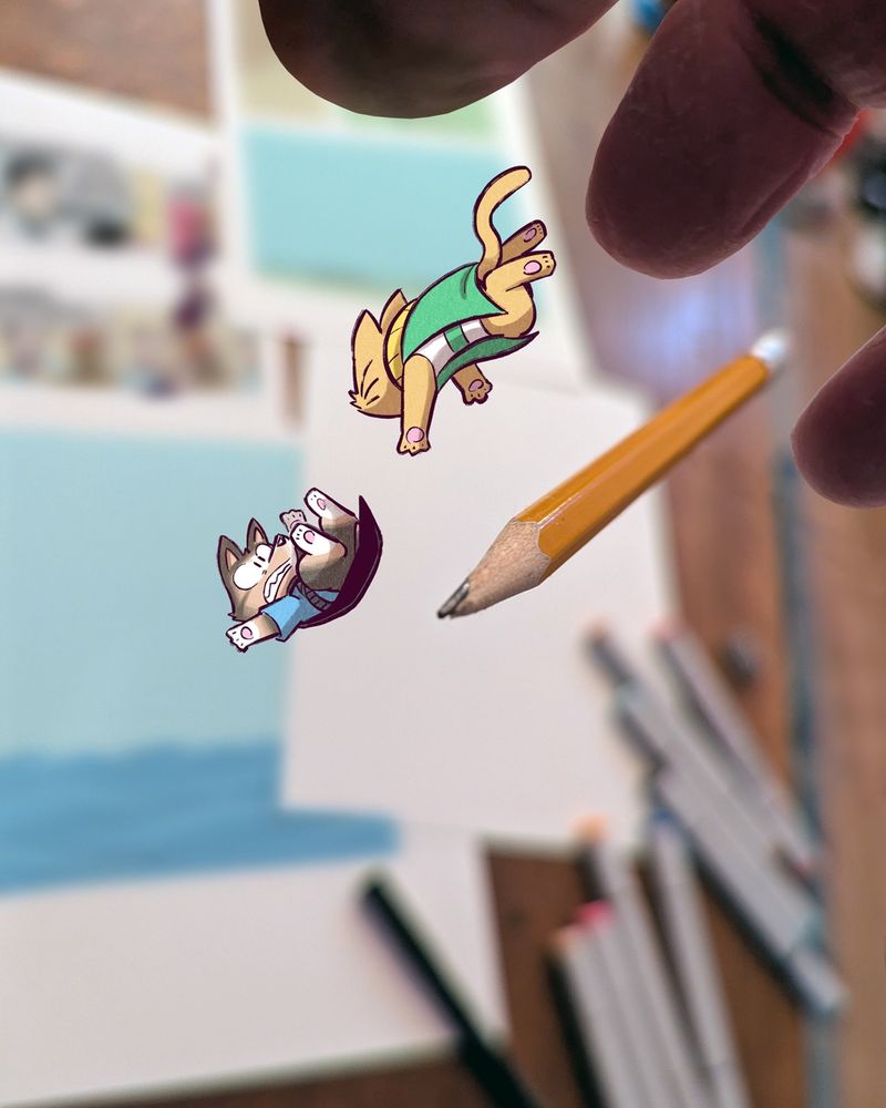 The animals and pencil plummet towards the table, which is covered with artwork and pens.