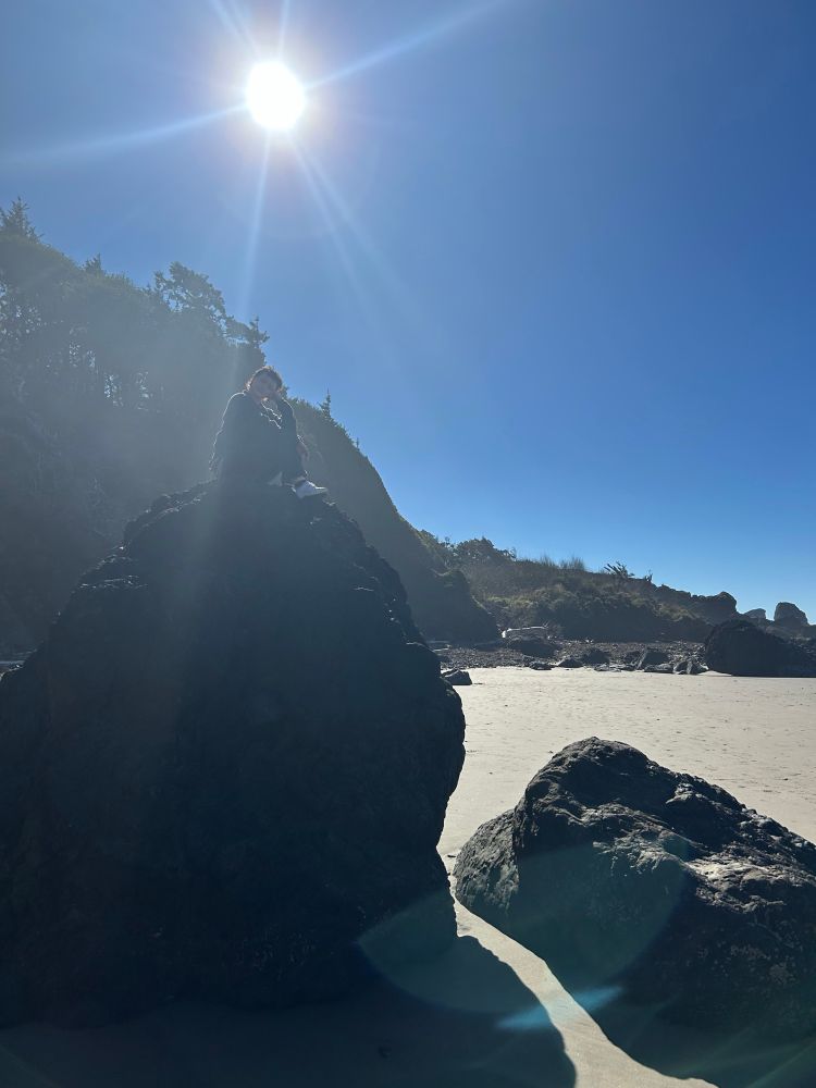 Picture of a sandy area with two large rocks and I’m sitting on one of them, facing the camera :)