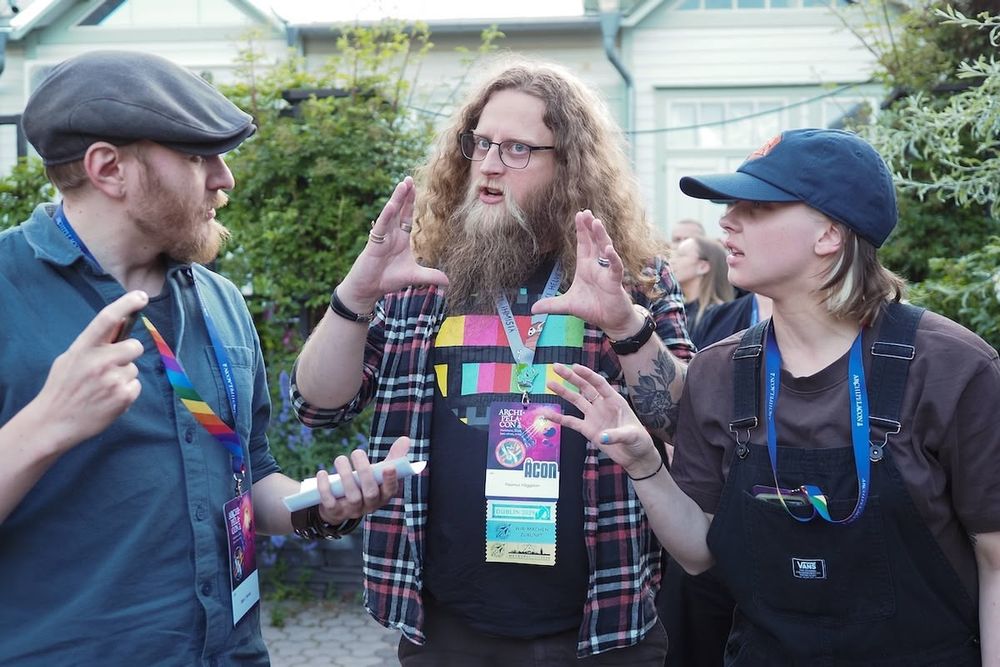 Three persons standing in a pub terrace garden, intensely debating an answer to a quiz question: hands in the air, with focused expressions