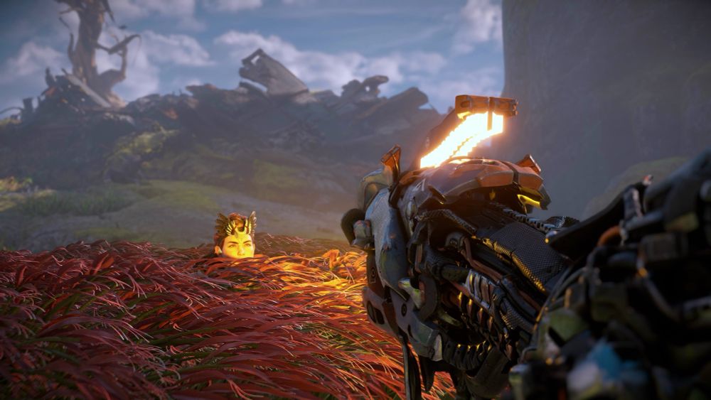 Horizon zero dawn Aloy crouched, lit by the yellow light of a watcher in the foreground 