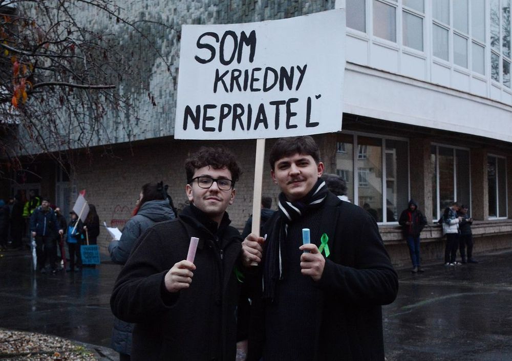 Demonstrierende mit Kreide in den Händen und Transparent: Som kriedny nepriatel´(Wortspiel: Ich bin der Kreidefeind, reimt sich auf Ich bin der Klassenfeind)