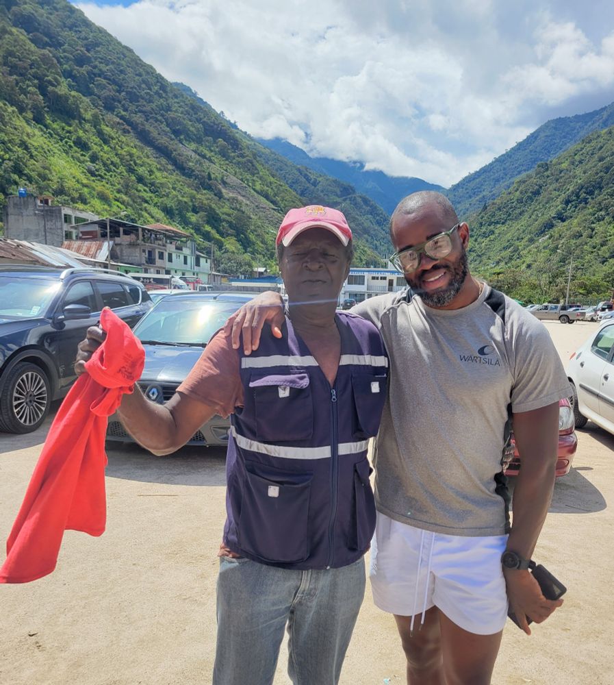 2 Black men standing in a dirt paved car park in the mountains of Ecuador 
