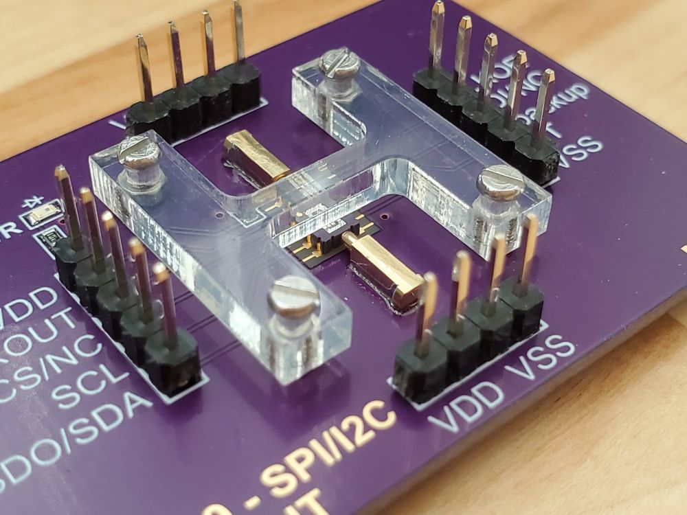 The pins of the IC are being aligned to the board's pads by the pogo pins.