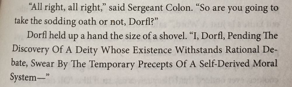 Picture of a page of the paperback I'm reading. The character Dorfl creates an atheist oath. "I, Dorfl, pending the discovery of a deity whose existence withstands rational debate, swear by the temporary precepts of a self-derived moral system