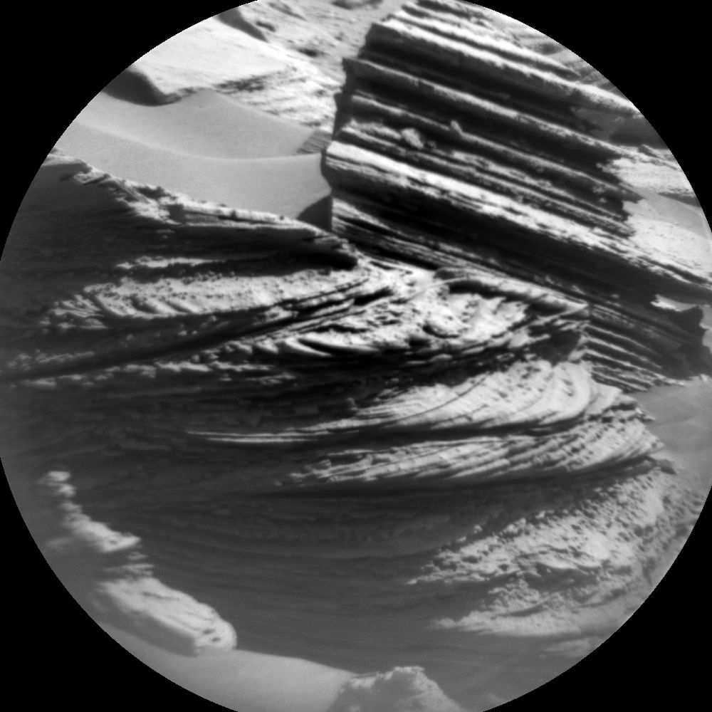 A monochrome photo of a rock. The rock contains several cross-bedded layers.