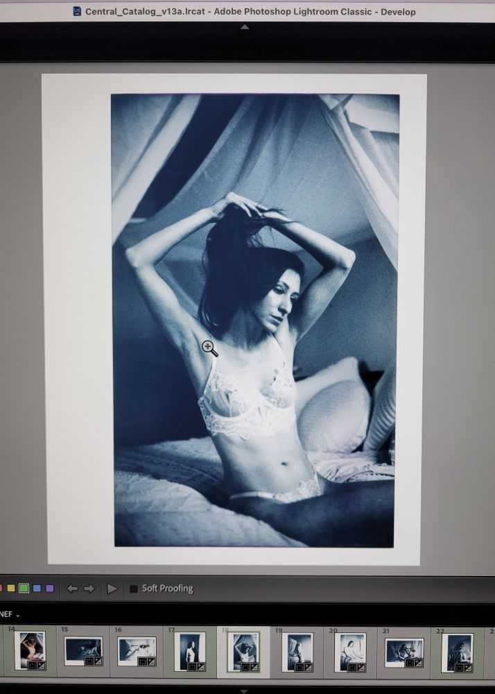 A preview of the scanned image of a monochrome instant photo of Kate. She is sat on a bed with a canopy, wearing light and lacy lingerie, and has her arms held slightly above her head as if playing with her hair.