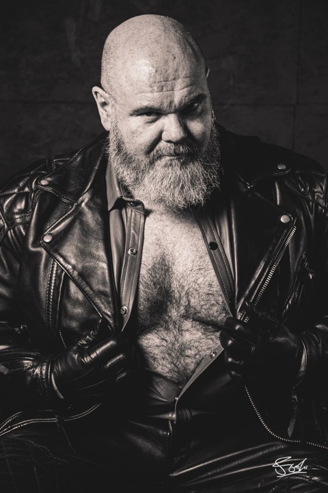 Leather bear exposing his open leather shirt and chest underneath.