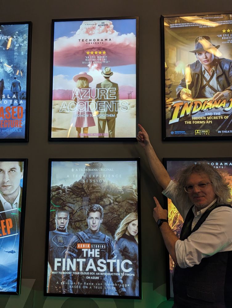 Rik standing in front of a movie poster for his conference session in a Barbenheimer style